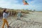 Happy siblings children running and having fun with kite on beach