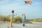 Happy siblings children running and having fun with kite on beach