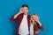 Happy siblings covering eyes with donuts, posing together over blue background