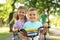 Happy siblings and  parents riding bicycles in park