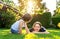 Happy siblings playing on green grass in garden backyard at sunset. Togetherness, little brother spending time with his teen siste