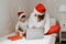 Happy siblings in red santa hats ordering Christmas gifts online paying using laptop