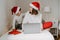 Happy siblings in red santa hats ordering Christmas gifts online paying using laptop