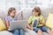 Happy siblings using technologies on sofa