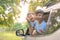 Happy siblings waving hands travel by car against blue sky. Summer road trip concept