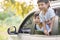 Happy siblings waving hands travel by car against blue sky. Summer road trip concept