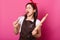 Happy singing baker wears kitchen apron smeared with flour, white t shirt, red headband, holds baking rolling pin and whisk.