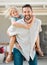 Happy single father giving his little daughter a piggyback ride outside in the garden. Smiling caucasian single parent