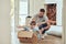 Happy single father pushing his little kids in homemade aeroplane cardboard box at home. Adorable little children