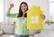 Happy single young woman smiling and holding paper house and keys to her new home