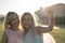 Happy sisters taking selfie after shopping in sunset image