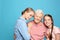 Happy sisters with their grandmother on light blue