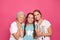 Happy sisters with their grandmother on pink