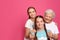 Happy sisters with their grandmother on pink background