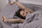 Happy sleepy girl brunette in burgundy top under grey sheets in bed. morning routine. good dream, sleeping
