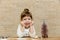 Happy small girl with Christmas tree.Brick wall background.Minimalist style.Christmas light