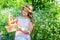 Happy small girl with fashion look in summer style hold harvest fruit basket on natural sunny lanscape in countryside