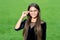 Happy small girl with long hair in fashion black dress fix corrective glasses with beauty look green grass sunny summer