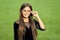 Happy small girl with long hair in fashion black dress fix corrective glasses with beauty look green grass sunny summer