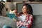 Happy smart pretty millennial african american woman sitting on sofa and reading book, enjoy free time