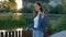 Happy smiled caucasian woman listening to music from the earphones, holding smartphone, dancing while walking outside