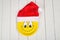 Happy smiley cartoon face on yellow paper plate and red Santa Claus hat