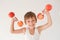 Happy smiling active strong little caucasian child in tank top lifting dumbbell made of apple during sport training workout