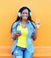Happy smiling african woman with headphones enjoying listens to music over orange