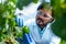 Happy smiling agro scientist seeing lab grown capsicum vegetable plant at greenhouse - conept of professional occupation