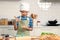 Happy smiling Asian boy wearing apron and chef hat, stirring and mixing eggs in glass bowl, cute child cooking meal at kitchen,