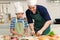 Happy smiling Asian father and son kid with apron and chef hat cooking meal together at kitchen, dad parent and boy child cutting