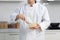 Happy smiling Asian man in white chef uniform with hat, stirring and mixing eggs in glass bowl. young baker man cooking meal food