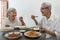 Happy smiling asian senior women eating Thai food,sitting at dining table in the house,old people talking and enjoy during