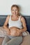 Happy smiling attractive young pregnant woman cradling her bare baby bump