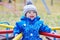 Happy smiling baby boy outdoors in autumn on playground