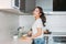 Happy smiling beautiful long hair asian girl young woman cuts lemon in her kitchen