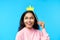 Happy smiling black woman with paper crown on stick on blue background
