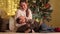 Happy smiling boy lying on mothers lap while she caressing him next to Christmas tree. Families and children celebrating