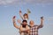 Happy smiling boy on shoulder dad looking at camera. Happy family. Child pilot aviator with paper airplane dreams of