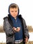 A happy smiling boy is standing on the bank of the river and holding a fish in his hands. The boy caught a fish. Autumn fishing