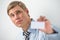 Happy smiling business man showing blank businesscard and dreaming, while leaning on wall at office