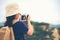 Happy smiling caucasian children asian girl backpack and holding camera for take a photo check in on mountain.