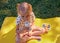 Happy smiling child girl drinking yogurt or milk outdoor at a summer picnic. Holding white plastic bottle and on face whiskers