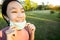 Happy smiling child girl is standing,taking off mask in green nature,breathe deep,woman enjoy breathing fresh air,relaxing in park