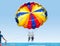 Happy smiling couple Parasailing on Tropical Beach in summer. Newlyweds under parachute hanging mid air. Having fun. Tropical