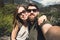 Happy smiling couple of students in love take selfie self-portrait while hiking in Yosemite National Park, California