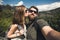 Happy smiling couple of students in love take selfie self-portrait while hiking in Yosemite National Park, California