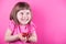 Happy smiling cute little girl holding pretty spotted gift box in her hands on bright pink background