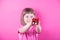 Happy smiling cute little girl holding pretty spotted gift box in her hands on bright pink background