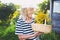 Happy smiling elderly senior woman in straw hat having fun posing in summer garden with flowers in basket. Farming, gardening,